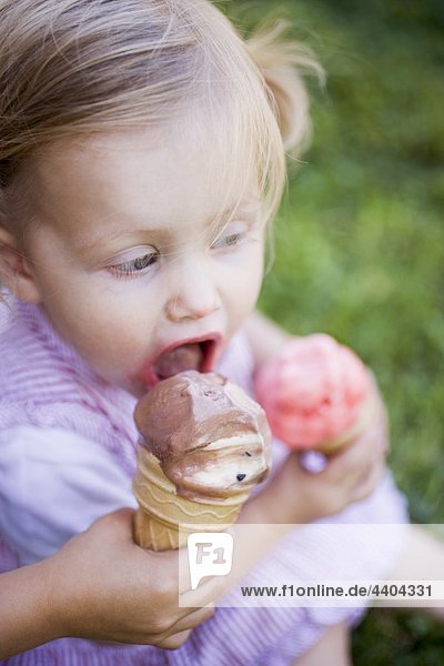 Kindes hand bietet kleines Mädchen einen lecken Eis