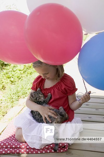 Kleines Mädchen halten Katze und Ballons (4. Juli USA)