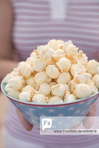 Frau hält Popcorn in Schüssel mit Sterne (4. Juli  USA)
