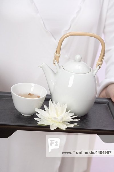 Frau hält Teekanne  Tee Schale und Seerose auf tray