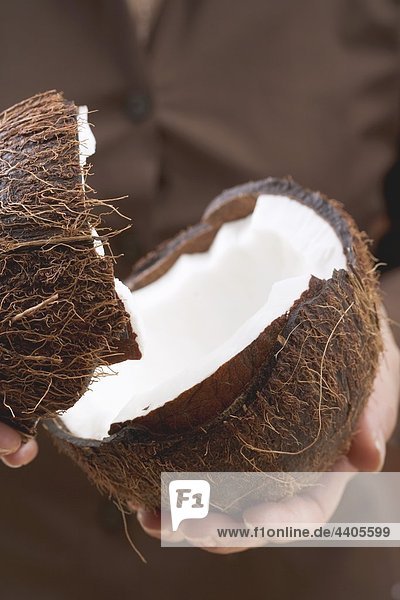 Halbierte Kokos hält hände