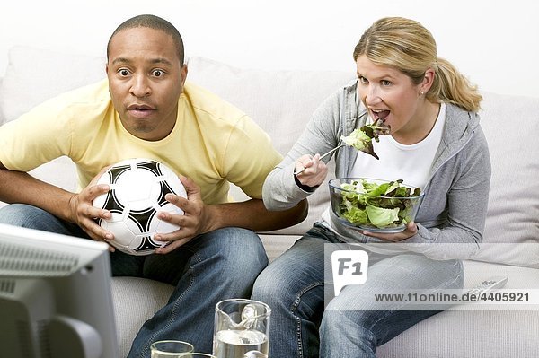 Couple in front of TV with football and salad