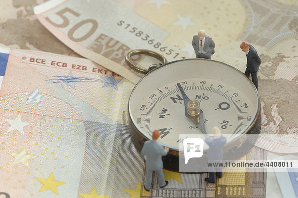 Figur auf Euro-Noten stehend und am Kompass beobachtend