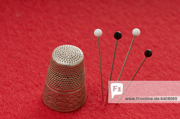Thimble and fixing pins on red background