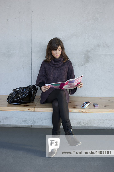 Woman sitting and reading magazine