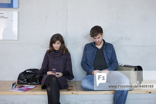 Germany,  Leipzig,  University students sitting and using mobile phone