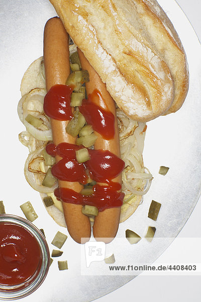 Hot dog with ketchup and onions in baguette.