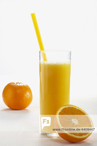 Frisch geschnittene und ganze Orangen und ein Glas Orangensaft