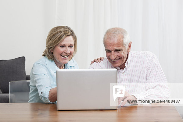 Senior Paar mit Laptop  lächelnd