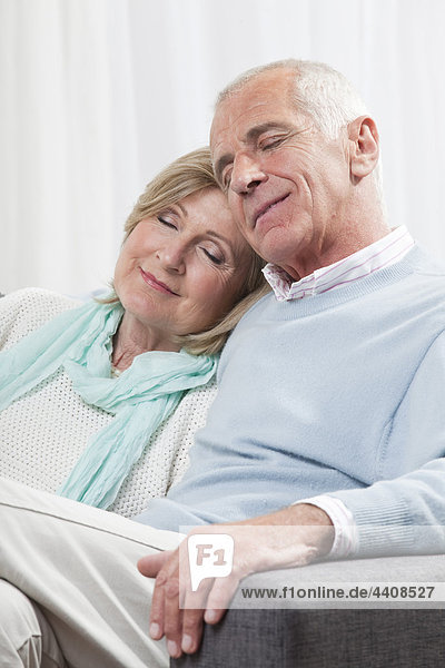 Senior couple sitting on couch  smiling  eyes closed