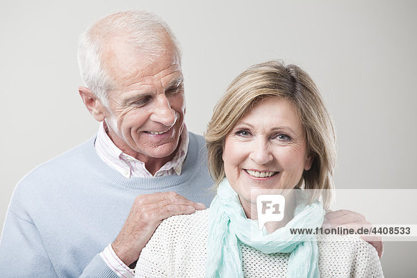 Seniorenpaar vor grauem Hintergrund  lächelnd