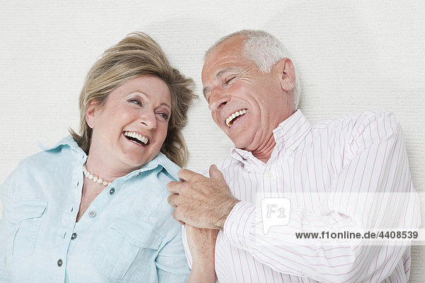 Seniorenpaar hält sich an den Händen und lächelt.