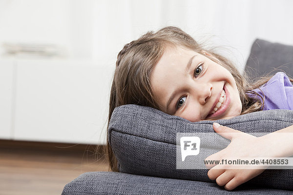 Nahaufnahme des Mädchens (6-7) auf der Couch liegend  lächelnd  Portrait