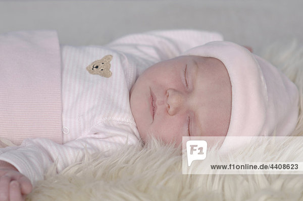 Baby Mädchen (0-1 Monate) schläft auf weißer Felldecke  Nahaufnahme