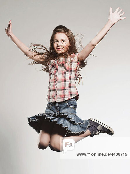 Girl (8-9) jumping with arms up  smiling