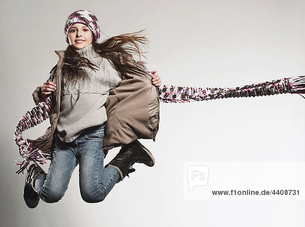 Girl (8-9) wearing jacket jumping  smiling  portrait