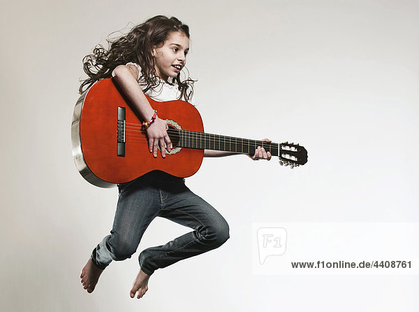 Girl (12-13) playing guitar and jumping