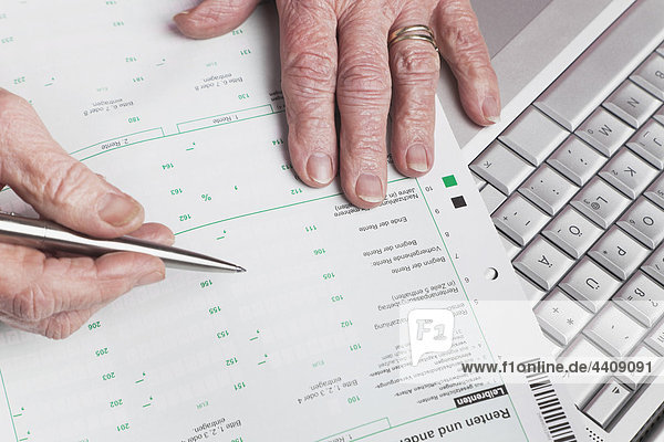 Deutschland  Seniorin mit Rentenbescheinigung und Laptop