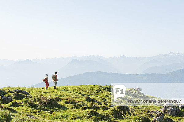 Young couple standing on mountaintop  looking at view.