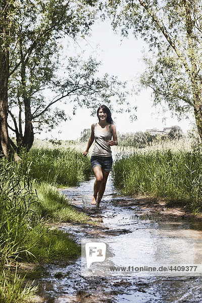 Young woman running in creek