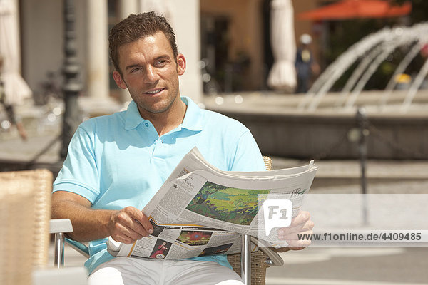Man sitting with newspaper  smiling