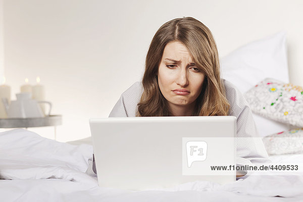Woman lying on bed with laptop