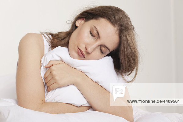 Woman holding pillow and sleeping  eyes closed