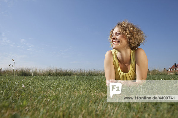 Frau auf Gras liegend und lächelnd