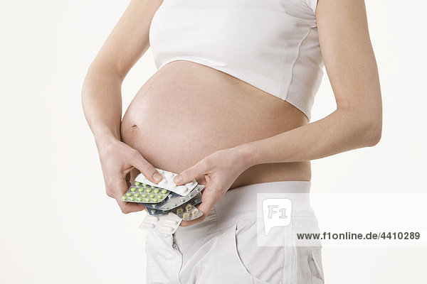 Schwangere Frau hält Tabletten  Mittelteil