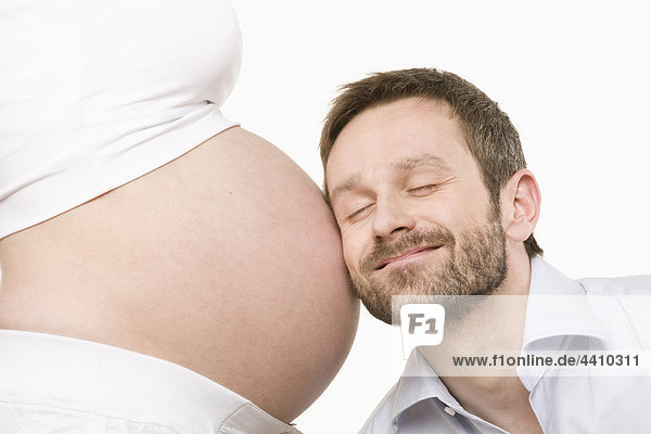 Mann hört auf den Bauch der Schwangeren  Augen geschlossen  Nahaufnahme