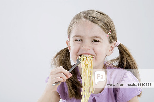 Girl (4-5) eating spagetti  smiling  portrait