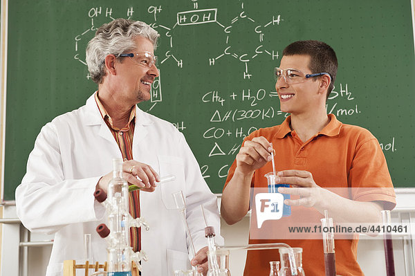 Deutschland  Emmering  Lehrer und Schüler beim Experimentieren im Chemieunterricht  lächelnd