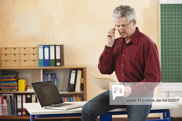Senior man sitting on table and holding file