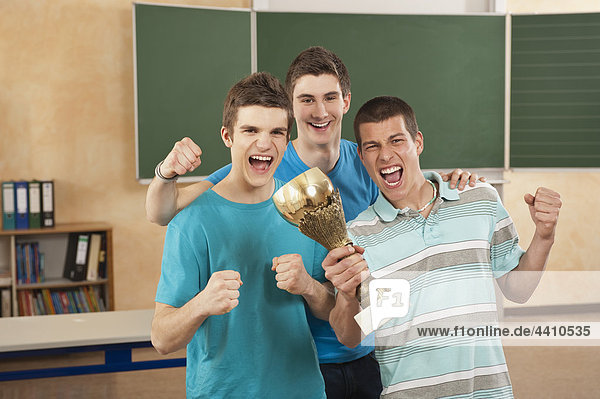 Deutschland Emmering Freunde mit Trophäe und geballter Faust lächelnd