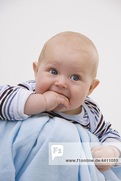 Baby Junge (6-11 Monate) mit Finger im Mund  wegschauend