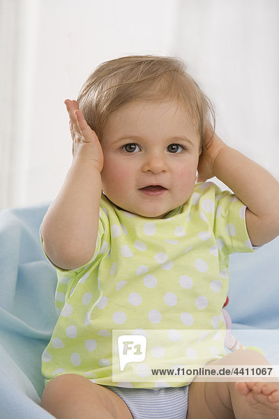 Baby Mädchen (6-11 Monate) übergibt Ohren  Portrait