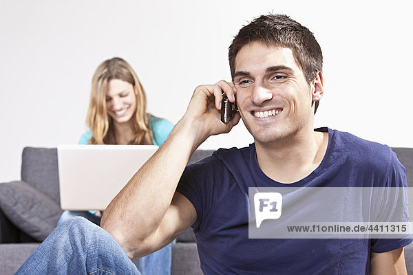 Man talking on mobile phone  woman using laptop in background
