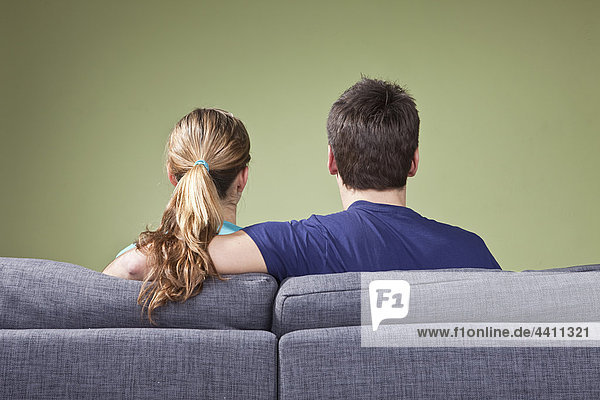 Junges Paar auf der Couch sitzend  Rückansicht