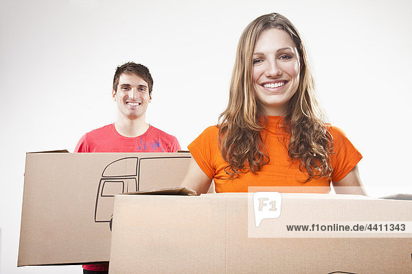 Young couple carrying cardboard boxes  smiling  portrait