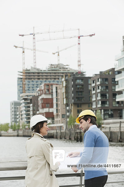 Mann und Frau mit Bauplan im Hafen