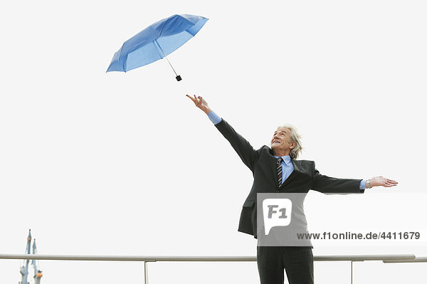 Deutschland  Hamburg  Geschäftsmann  der versucht  den Regenschirm zu fangen.