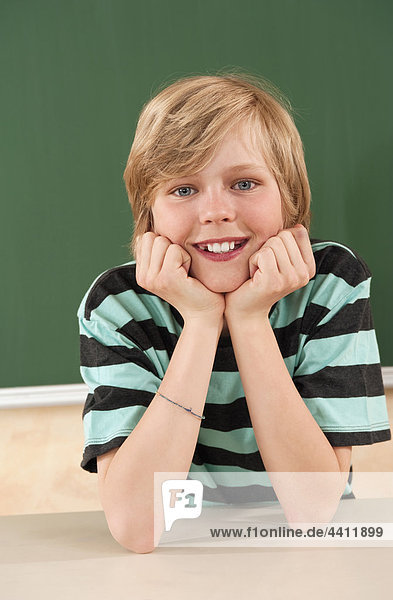 Boy (12-13) smiling with head in hand  portrait