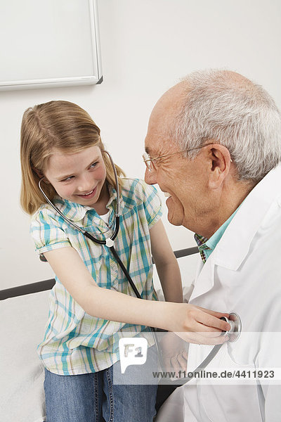 Mädchen (8-9) hört Herzschläge des Arztes  lächelt