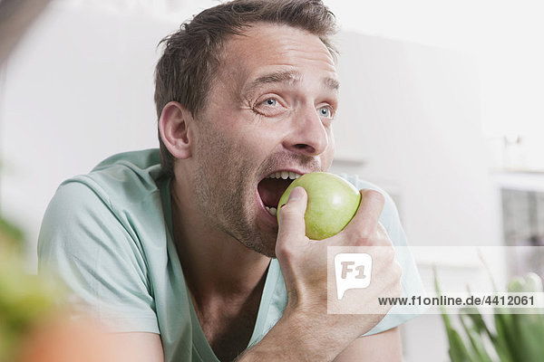 Deutschland  Mann beim Essen am grünen Apfel  Nahaufnahme