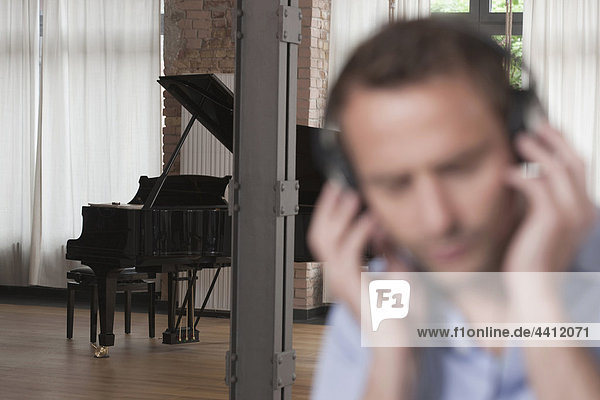 Deutschland  Mann hört Musik mit Klavier im Hintergrund