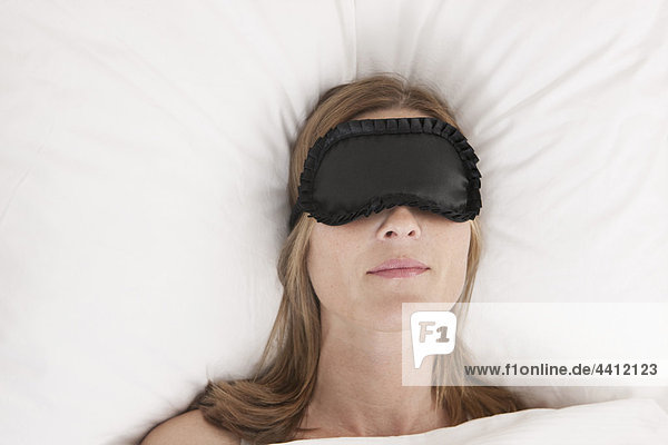 Deutschland  Frau mit Augenmaske auf dem Bett liegend