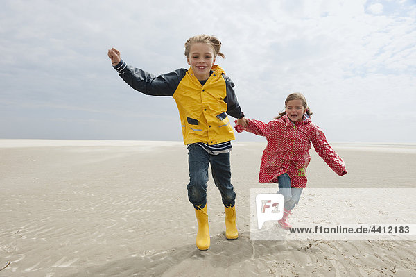 Deutschland  St. Peter-Ording  Nordsee  Kinder (6-9) beim Händchenhalten und Laufen am Strand