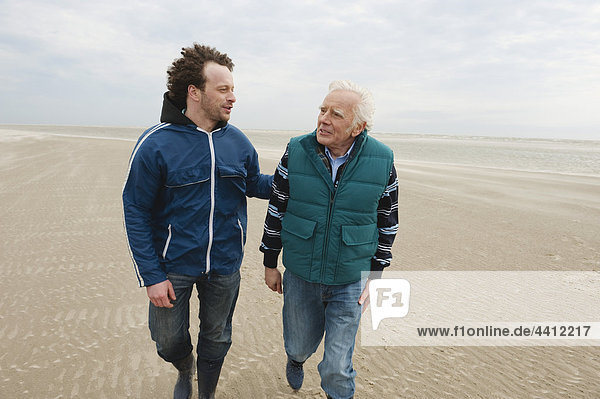 North Sea  Senior man and son walking on beach