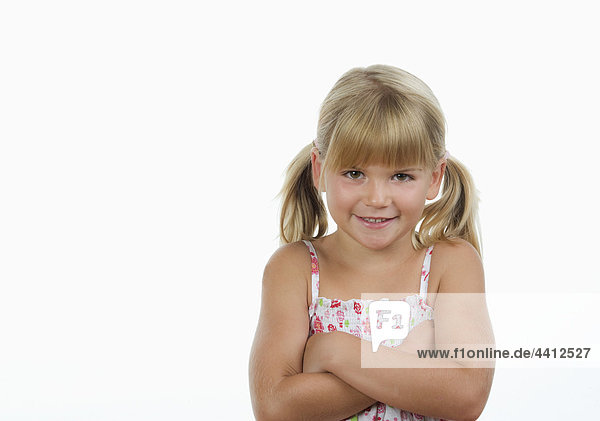 Girl (4-5) with arms crossed against white background  smiling  portrait