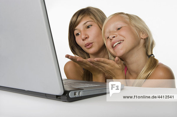 Two girls (10-11) looking at laptop and blowing a kiss